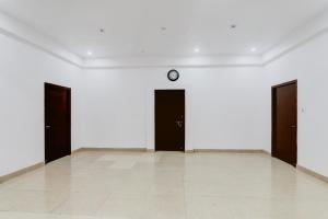 a room with three doors and a clock on the wall at Super Hotel O Insaf Nagar Munshipuliya Formerly Vibrant in Lucknow