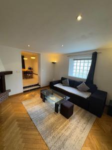 a living room with a black couch and a glass table at Maison conviviale - Proche aéroport Roissy in Le Blanc-Mesnil