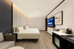 Atour Hotel Wujiaochang QuyangBailian ShoppingMall Shanghai في شانغهاي: غرفة فندقية مع سرير وتلفزيون بشاشة مسطحة