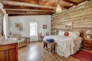 une chambre avec un lit et un mur en bois dans l'établissement Historic Log Cabin Retreat Near Town on 5 Acres!, à Fredericksburg