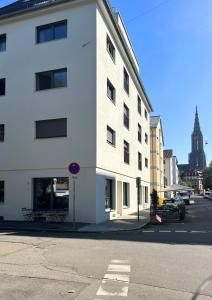 a white building on the side of a street at MI Apartment Ulm Design Studio by MAMO INTERIORS in Ulm