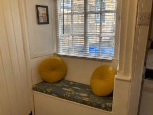 two orange ottomans sitting on a bench in a window at Endways Cottage in Robin Hood's Bay