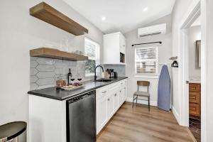 a kitchen with white cabinets and a black dishwasher at The Grove B Stylish Cottage - Walk to Main in Fredericksburg