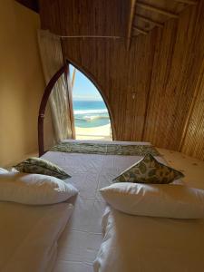 une chambre avec un lit avec vue sur l'océan dans l'établissement Manta Villa - Frontbeach Bamboo Eco Villa - Kini Village, à Sekongkang