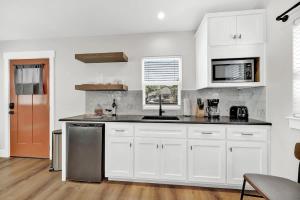 a kitchen with white cabinets and a stainless steel refrigerator at The Grove B Stylish Cottage - Walk to Main in Fredericksburg