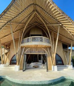 un grand bâtiment en bois avec un balcon et une piscine dans l'établissement Manta Villa - Frontbeach Bamboo Eco Villa - Kini Village, à Sekongkang