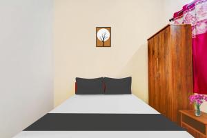 a bedroom with a bed and a wooden cabinet at Super Hotel O Okkilipalayam in Coimbatore +26 photos