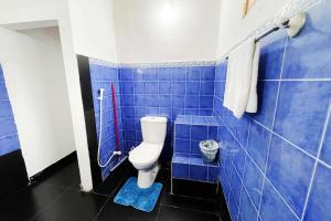 a blue tiled bathroom with a toilet and a shower at Tree Breeze in Negombo