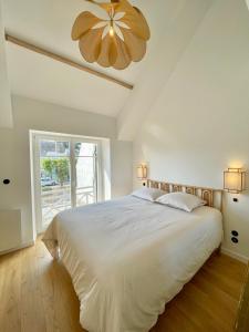 Un dormitorio con una gran cama blanca y una gran ventana. en Les oiselieres, plages a pieds, en Carnac