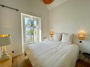 Una cama blanca en una habitación con ventana. en Les oiselieres, plages a pieds, en Carnac