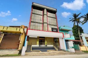 a building with a palm tree in front of it at Super Collection O Kushal Nagar Near KSRTC Bus Stand in Madikeri