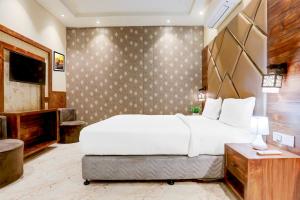 a bedroom with a large white bed and a television at Palette by CheckIn Patliputra Colony Formerly The Aurum in Patna +28 photos