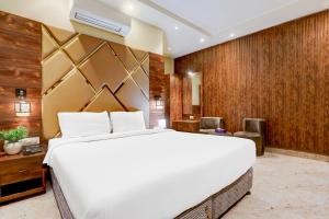 a bedroom with a large white bed and wooden walls at Palette by CheckIn Patliputra Colony Formerly The Aurum in Patna