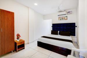 Super Hotel O Mahabalipuram Formerly The Posh Palace في مهاباليبورام: غرفة نوم بسرير كبير في غرفة بيضاء