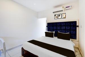 Super Hotel O Mahabalipuram Formerly The Posh Palace في مهاباليبورام: غرفة نوم بسرير أبيض وجدار أزرق +24 صورة