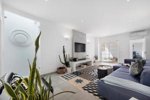 a living room with a blue couch and a tv at Casa Surfer’s Sanctuary - Algarve in Vila do Bispo