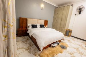 a bedroom with a large bed and a fan at The Nest Kampala in Katale