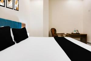 a white bed with black pillows in a bedroom at Hotel O Kota Railway Junction Formerly Formerly Aagam Inn in Kota