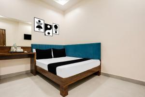 a bedroom with a bed with a blue headboard at Hotel O Kota Railway Junction Formerly Formerly Aagam Inn in Kota +28 photos