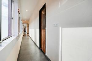 a hallway with white walls and a wooden door at Hotel O Kota Railway Junction Formerly Formerly Aagam Inn in Kota