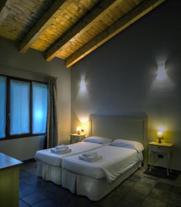 ein Schlafzimmer mit einem Bett mit zwei Tischen und zwei Lampen in der Unterkunft Agriturismo Le Case Di Campagna in Dossobuono