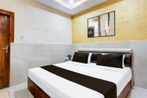 um quarto com uma grande cama branca com almofadas pretas em Super Hotel O Mall Road Gwalior formerly Rama inn em Gwalior