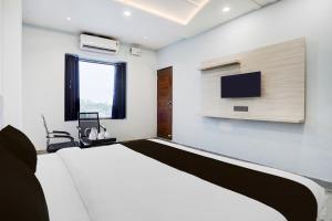 a bedroom with a bed and a tv on the wall at Super Hotel O Hanuman Gadi Formerly Alankar Lawn in Varanasi