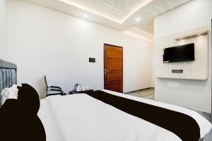 a bedroom with a bed and a tv on a wall at Super Hotel O Hanuman Gadi Formerly Alankar Lawn in Varanasi