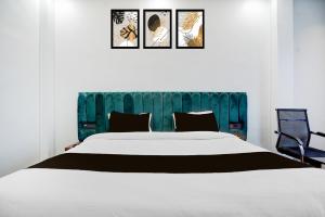 a bedroom with a large white bed and a blue headboard at Super Hotel O Hanuman Gadi Formerly Alankar Lawn in Varanasi