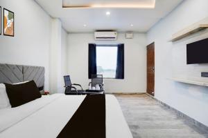 a bedroom with a large bed and a tv at Super Hotel O Hanuman Gadi Formerly Alankar Lawn in Varanasi +26 photos