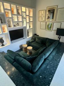 a large green couch in a living room with a television at Maison EMERAUDE in Rabo de Peixe
