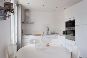カンヌにあるAppartement design proche Croisette, classé 4 étoilesの白いキッチン(白いテーブルと椅子付)