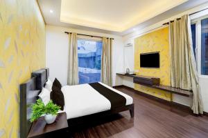 Super Townhouse Sector 51 Noida Near Metro Station في نويدا: غرفة فندق مع سرير وتلفزيون