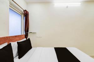 Un dormitorio con una cama con almohadas blancas y negras. en Super Hotel O Neredmet Road, en Hyderabad