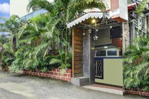 a house with palm trees in front of a door at Hotel O Porvorim Near Mall De Goa in Goa