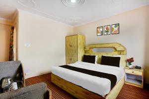 a bedroom with a large bed and a chair at Hotel O Aleo Near Mall Road Formerly Aman Cottage in Manāli