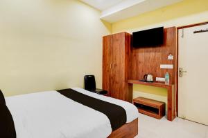 a hotel room with a bed and a tv at Super Collection O Vadapalani Metro Station Formerly Pineapple Guest House in Chennai