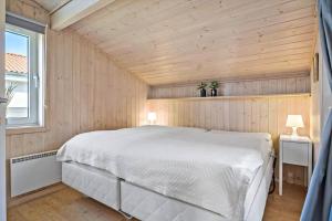 a bedroom with a white bed in a wooden room at BL222-Blokhus-Jens-Baerentsvej-16 in Blokhus