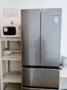a refrigerator in a kitchen with a microwave at Fanhua Life IN Nanjing West Road Store 2 in Shanghai