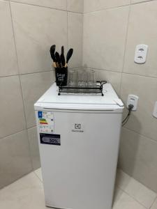 a white refrigerator with a container of utensils on top of it at Residencial Portela 08C in Fortaleza