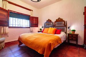 a bedroom with a bed with orange sheets and a window at Edomus Castillo de las Guardas in Seville +49 photos
