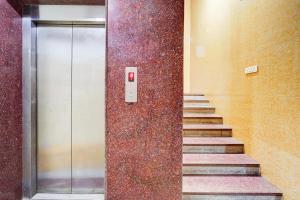 a hallway with stairs and a metal door with a wall at Super Hotel O Porur Formerly Jeya's Elite in Chennai
