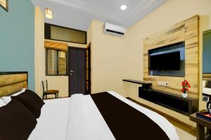 a bedroom with a bed and a flat screen tv at Super Collection O ISKCON Radha Govind Formerly Hotel Shivom in Indore