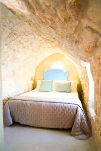 Un dormitorio con una cama en una pared de piedra. en Dimora Zazzù - nel CUORE della MAGIA di OSTUNI, en Ostuni