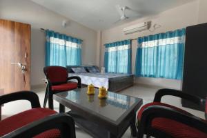 Una sala de estar con una cama, una mesa y sillas. en Banobitan Resort, en Lataguri