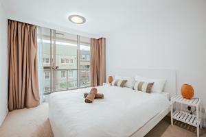 a white bedroom with a large bed and a window at 2 Bedroom Apartment Pyrmont with Pool and Gym Access in Sydney