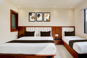 two beds in a hotel room with three pictures on the wall at Super Townhouse Taj Nagri Phase 2 Formerly Grand Rivera in Agra