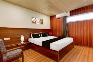 a bedroom with a bed and a chair and a window at Super OYO Hotel O Machilipatnam in Machilīpatnam