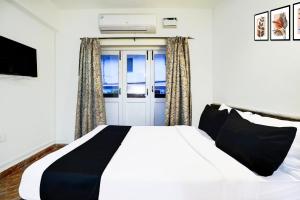 ein Schlafzimmer mit einem weißen Bett und einem Fenster in der Unterkunft Collection O Holiday Street Calangute Formerly Shruti Resort in Goa + 24 Fotos
