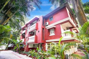 ein rotes Gebäude mit Palmen davor in der Unterkunft Collection O Holiday Street Calangute Formerly Shruti Resort in Goa